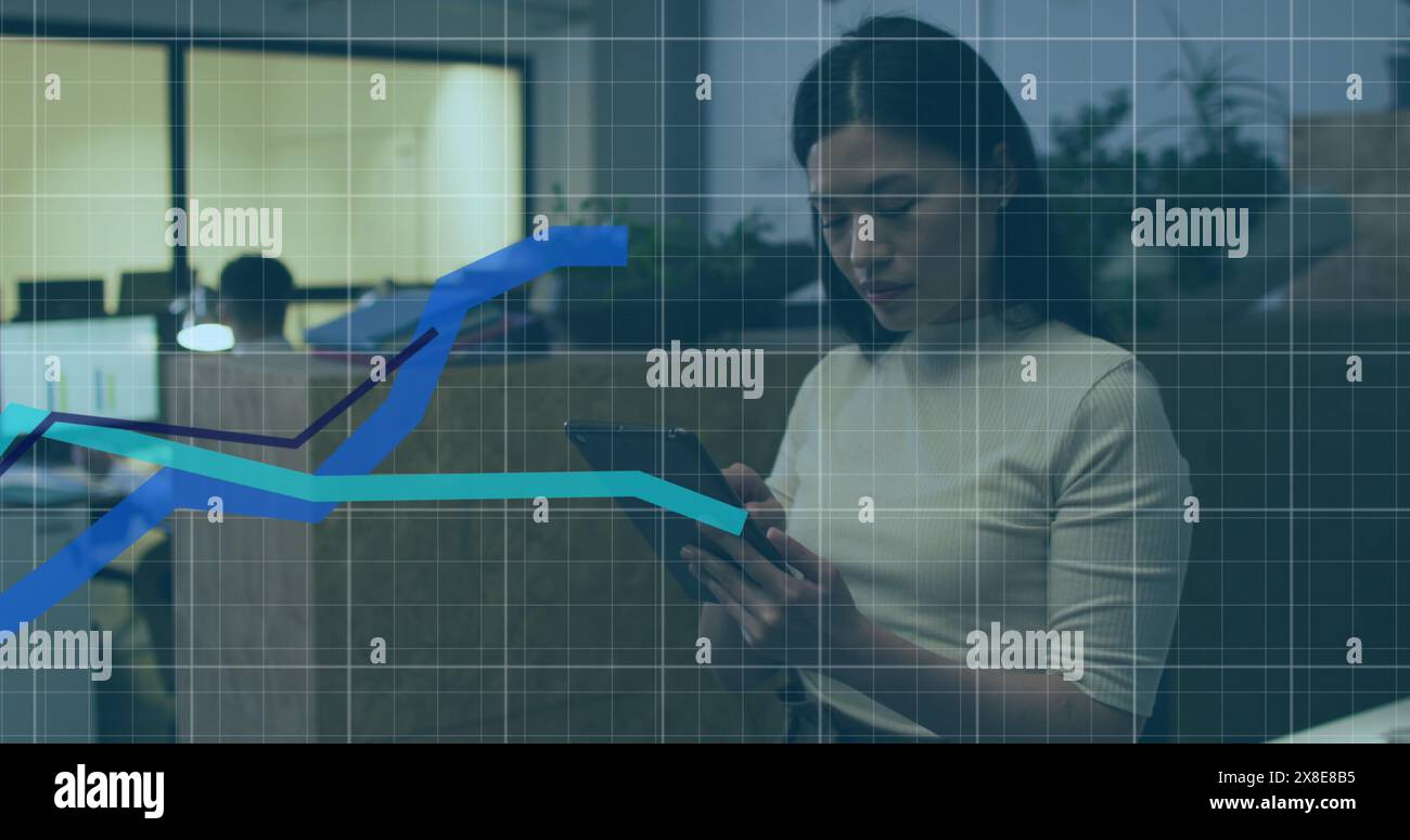 Immagine di grafici sulla griglia contro una donna d'affari asiatica che utilizza un tablet digitale in ufficio Foto Stock