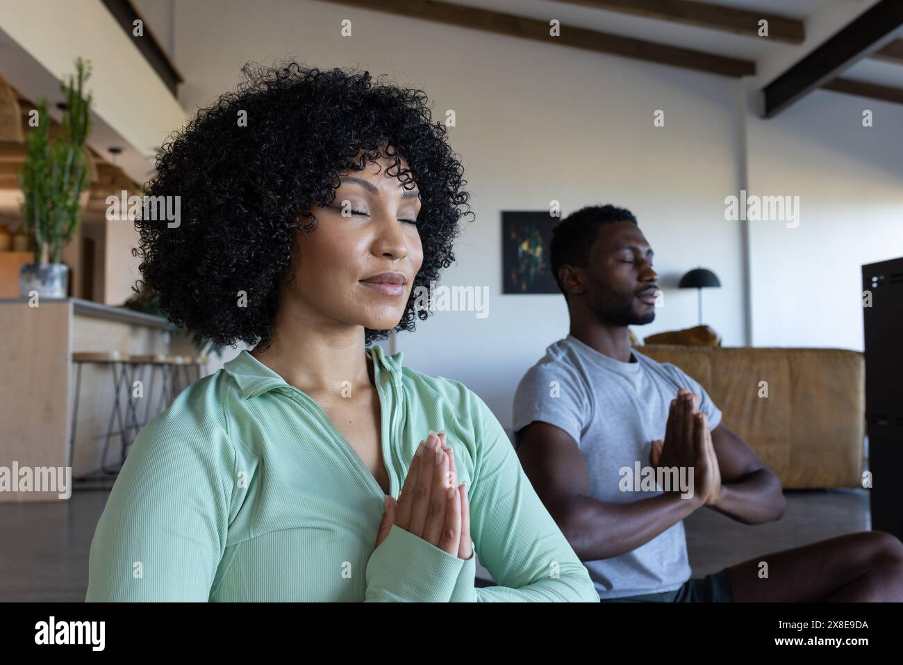 Una coppia diversa a casa, che pratica yoga insieme Foto Stock