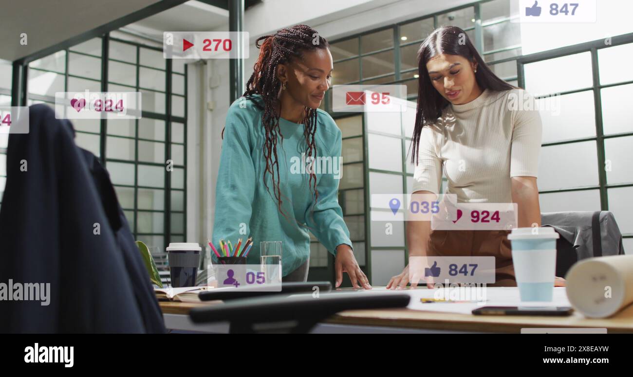 Immagine di numeri e icone che cambiano nelle barre di notifica, colleghi di sesso femminile che condividono idee Foto Stock