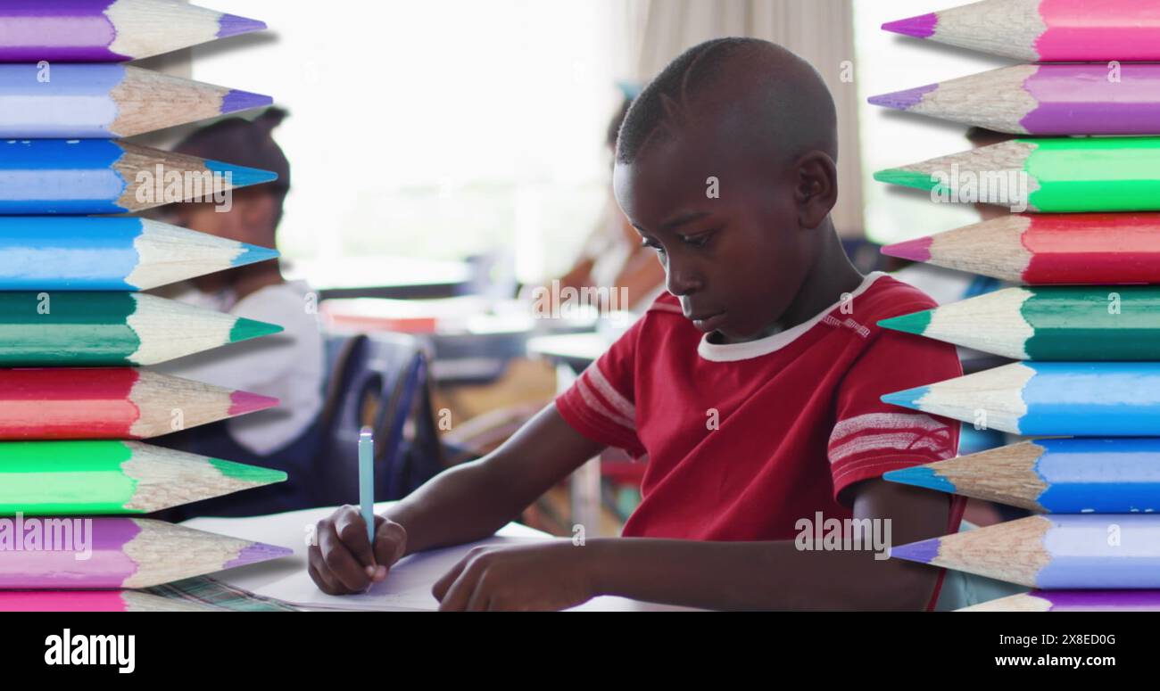 A scuola, ragazzo/studente afroamericano che indossa camicia rossa concentrandosi sulla scrittura Foto Stock