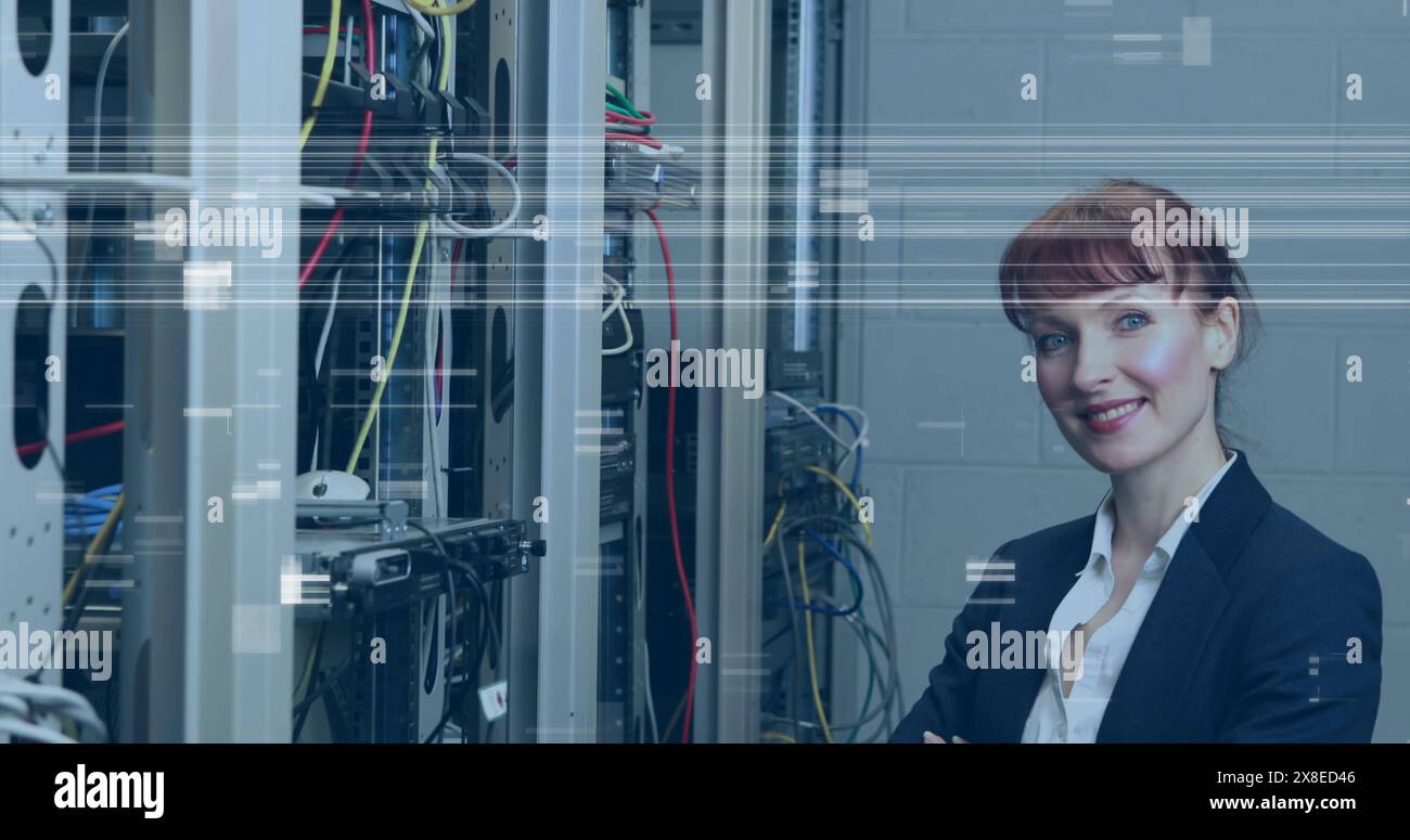 Donna caucasica in piedi davanti ai rack server, sorridente Foto Stock