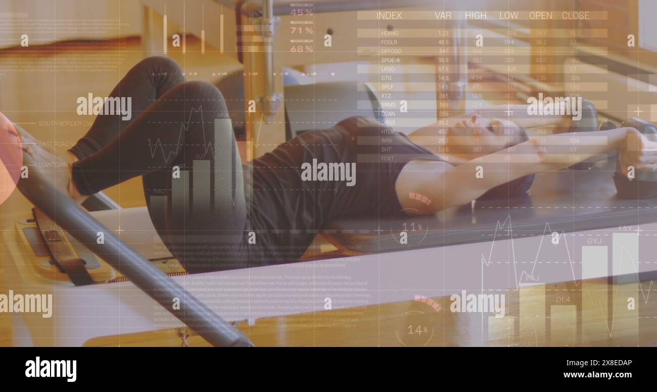 Donna caucasica che indossa abbigliamento sportivo nero, si allena su Pilates Reformer Foto Stock