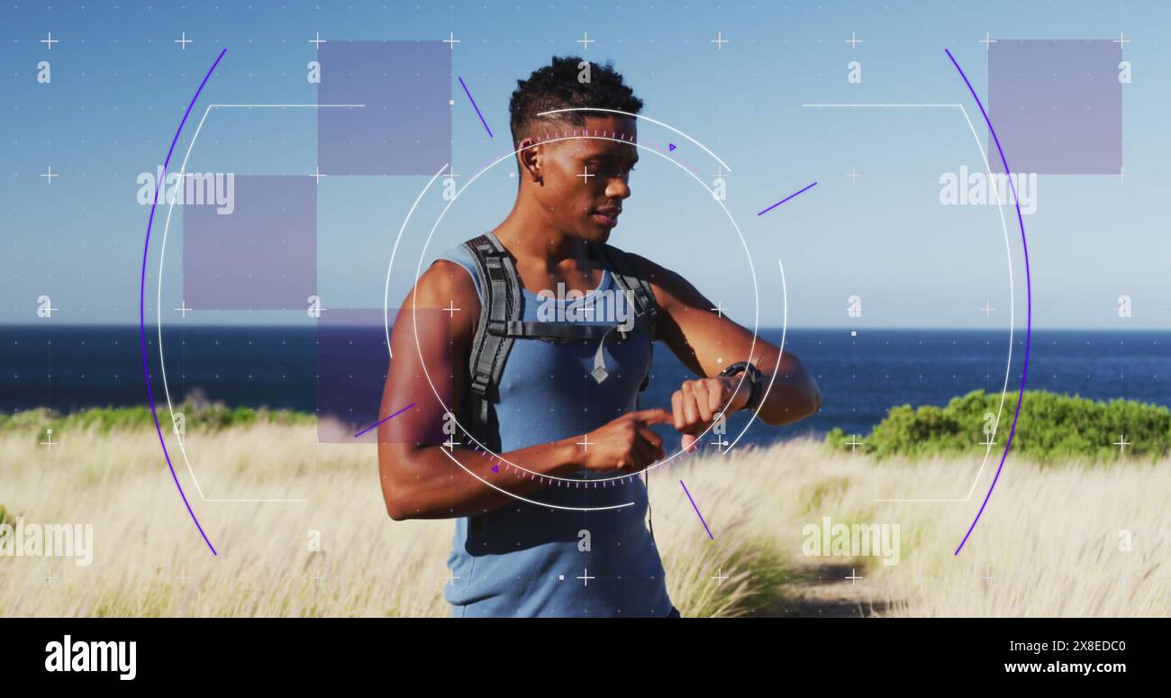 Allenatore birazziale maschile, indossa outfit fitness, controlla lo smartwatch in riva al mare Foto Stock