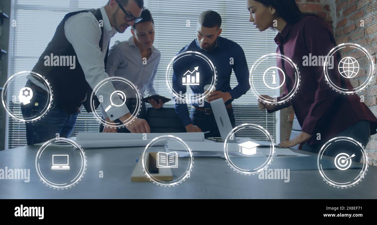 Immagine di icone digitali contro colleghi diversi che discutono insieme su un piano in ufficio Foto Stock