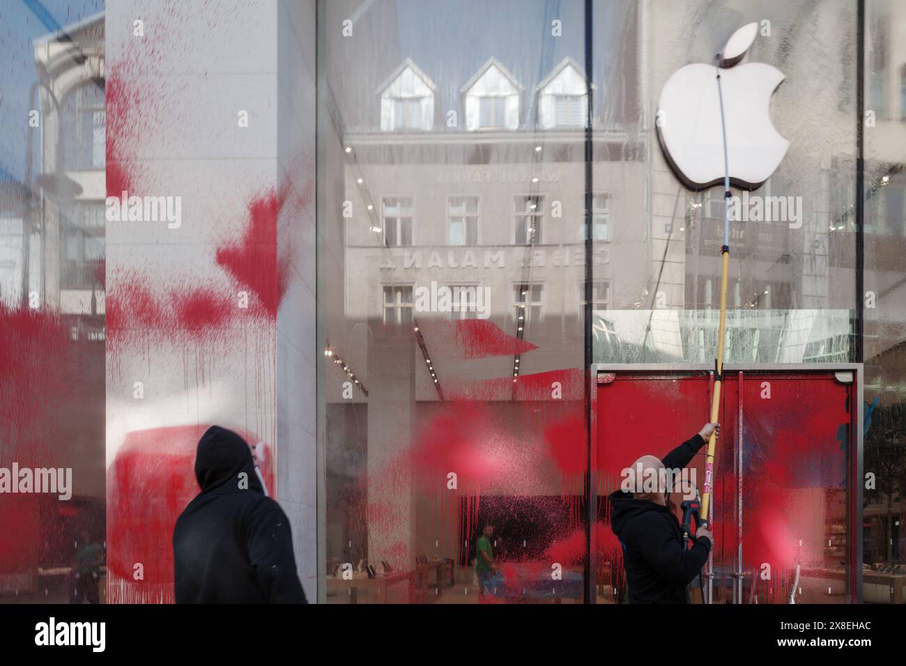 Berlino, Germania - 17 MAGGIO 2024: I lavoratori puliscono la vernice rossa macchiata sulla facciata di vetro di un Apple Store. Foto Stock