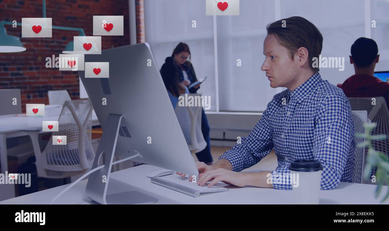 Immagine della forma del cuore in buste sull'uomo birazziale che lavora sul desktop in ufficio Foto Stock