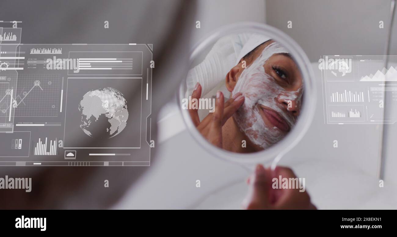 Immagine di grafici, globi su donna birazziale che guardano allo specchio e che applicano crema sul viso Foto Stock