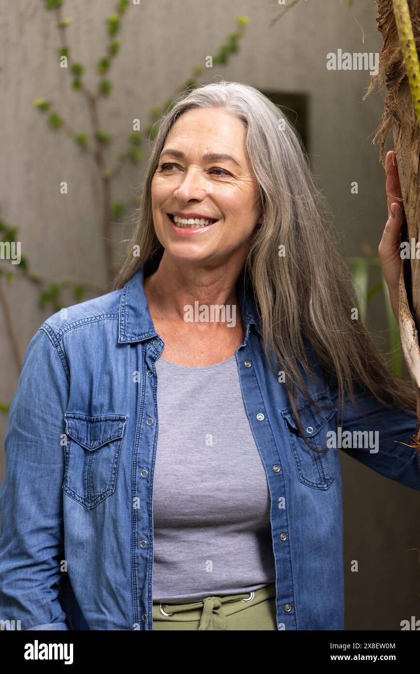 All'aperto, donna caucasica anziana con lunghi capelli grigi e occhi blu sorridenti Foto Stock