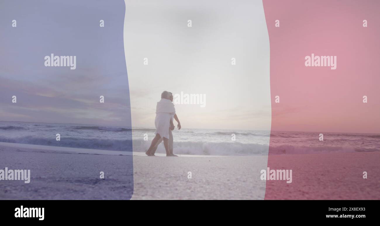 Immagine della bandiera della francia su una coppia birazziale senior che cammina in spiaggia Foto Stock