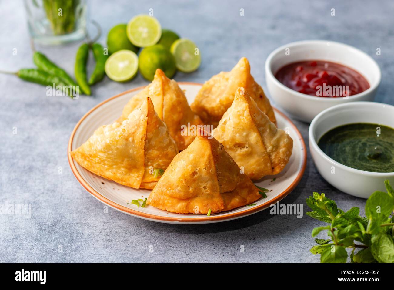 Samosa, pasticceria ripiena di patate, croccante, saporito, popolare spuntino indiano servito con tè chutney di pomodoro e menta. Foto Stock