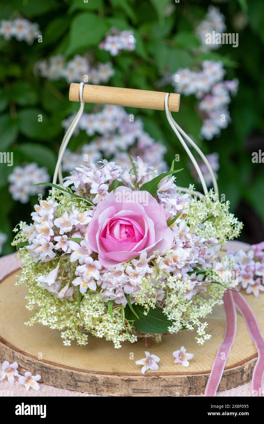 Romantica composizione floreale con rosa rosa Olivia Rose Austin, fiori anziani e fiori di bosco di bellezza in un cestino Foto Stock