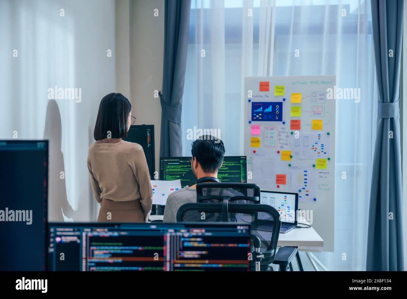 Discussione degli sviluppatori di software asiatici sul progetto di codifica sullo schermo del computer presso l'ufficio Moden Foto Stock