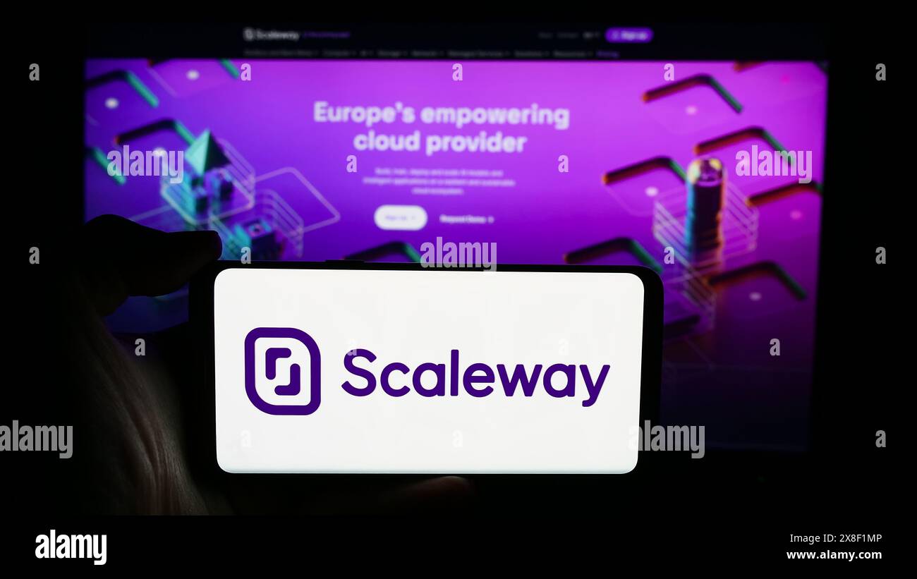 Persona che detiene un cellulare con il logo dell'azienda francese di cloud computing Scaleway SAS davanti alla pagina Web aziendale. Mettere a fuoco il display del telefono. Foto Stock