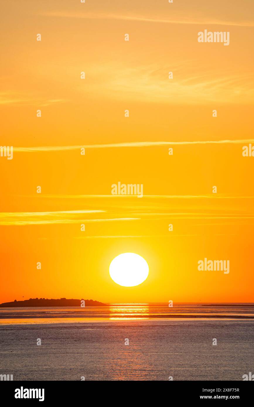 Pittoresco, dorato e magnificamente bellissimo tramonto sul mare, l'isola di Langluetjen II lontana, la palla del sole appena sopra l'orizzonte, arancione che risplende Foto Stock