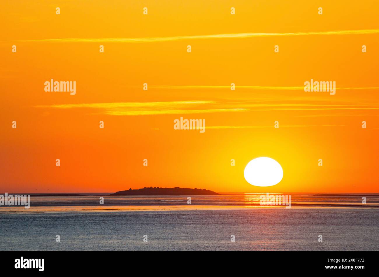 Pittoresco, dorato e magnificamente bellissimo tramonto sul mare, l'isola di Langluetjen II lontana, la palla del sole appena sopra l'orizzonte, arancione che risplende Foto Stock