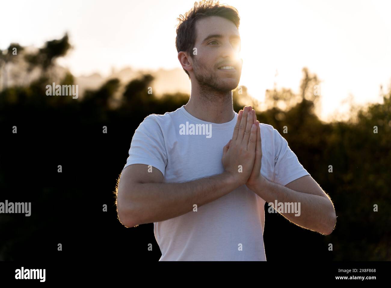 Un uomo pratica yoga in natura al tramonto Foto Stock
