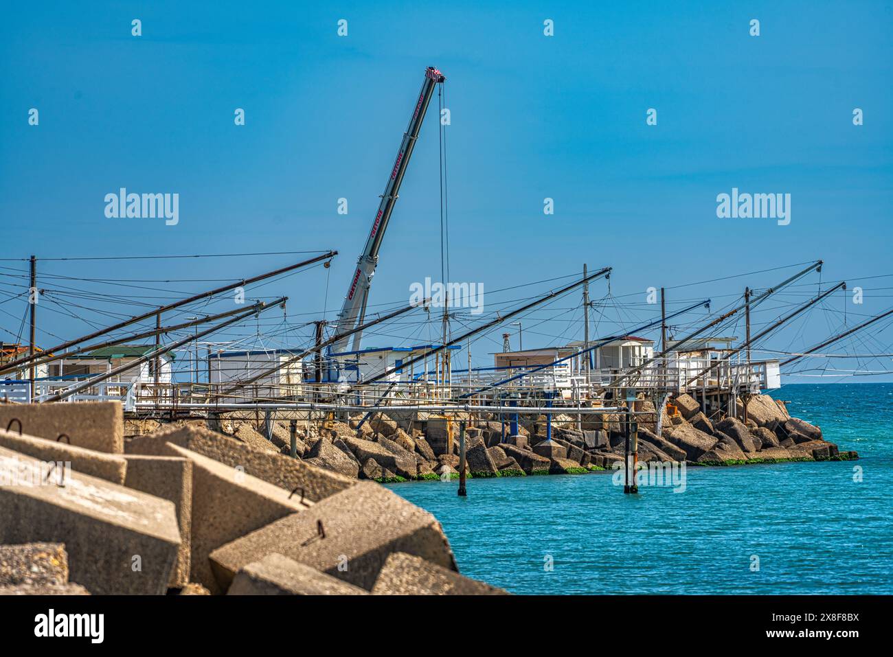 Nel porto di Giulianova i "caliscendi", strutture in legno utilizzate per la piccola pesca che si tuffano dalle rocce verso il mare. Abruzzo Foto Stock
