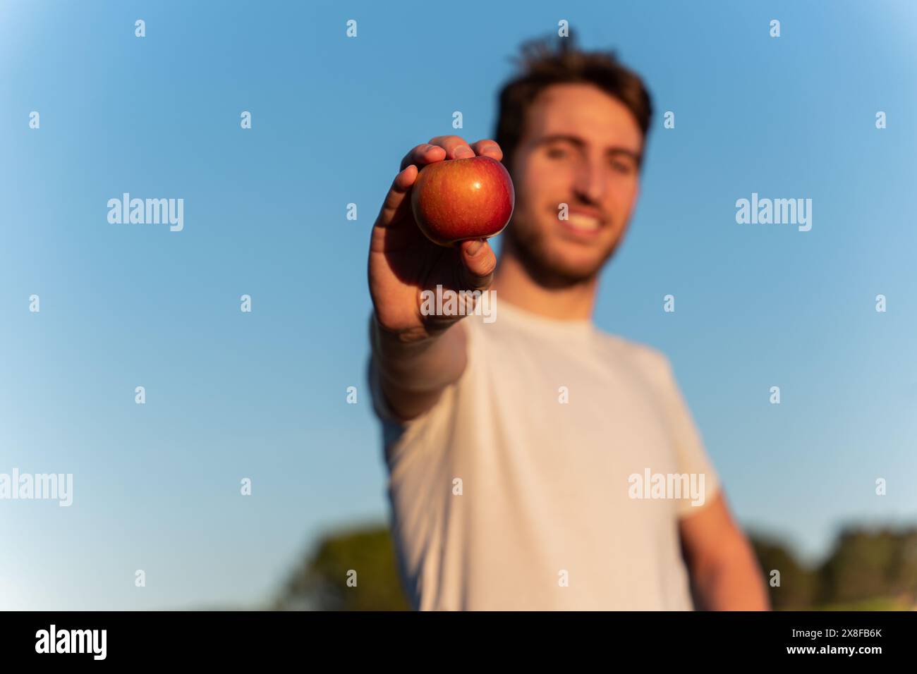 Uomo attraente che tiene in mano una mela. Stile di vita sano, dieta equilibrata e cibo naturale Foto Stock