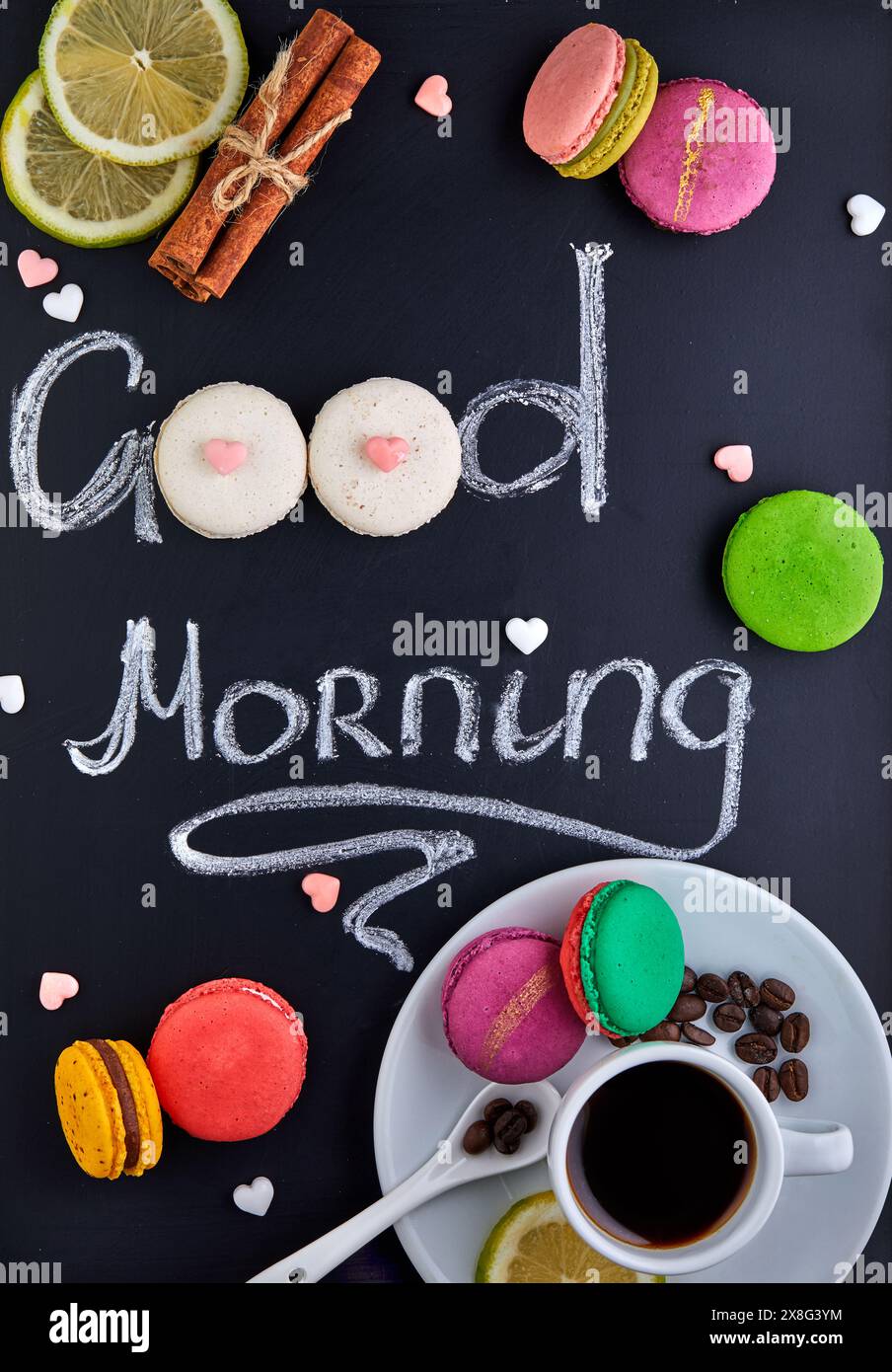 Bella lavagna con le parole "Buongiorno" scritte in un bellissimo font. Macaron e una tazza di caffè, ideali per essere collocati in una panetteria o in una caffetteria Foto Stock