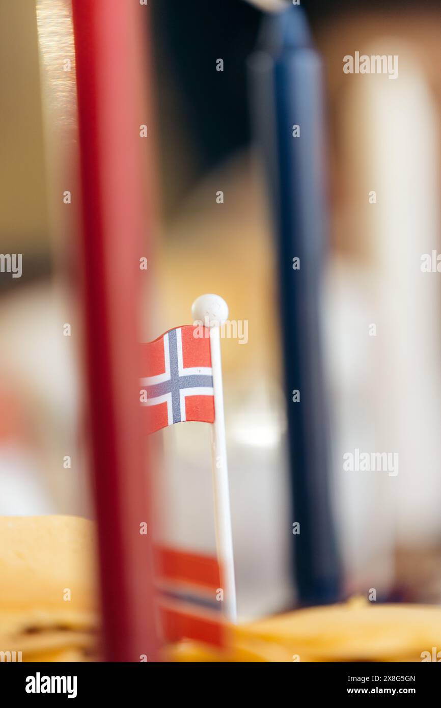 Primo piano della bandiera norvegese in miniatura accanto alle candele rosse e blu che simboleggiano il giorno della costituzione norvegese, il 17 maggio. Foto Stock