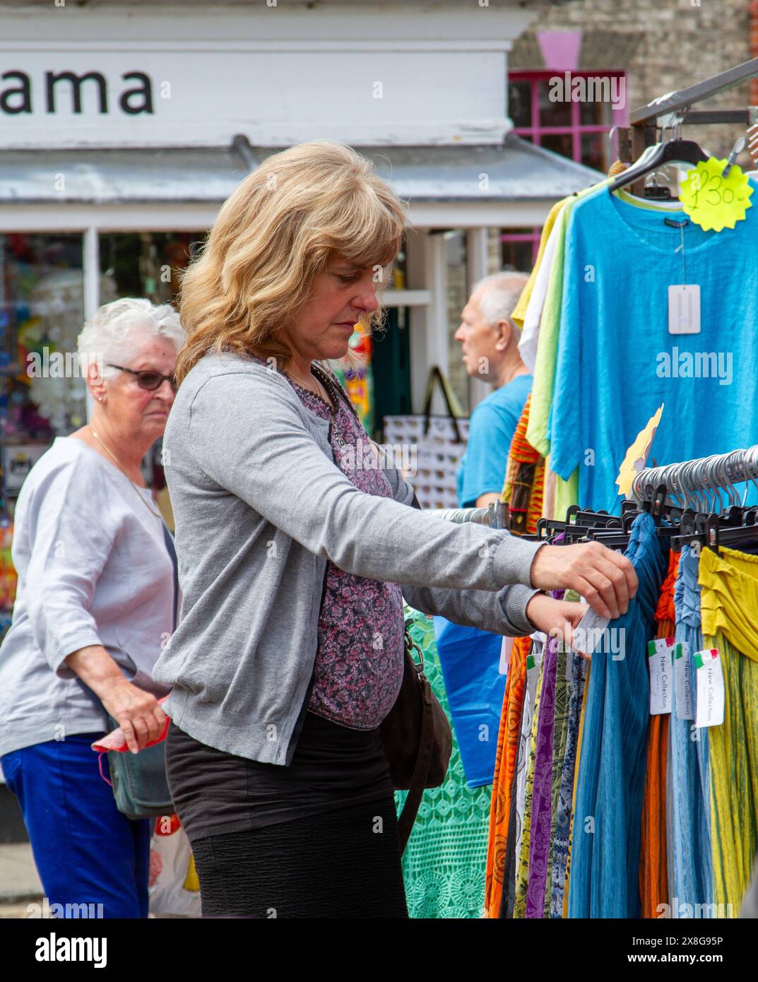 Una giornata di sole per il mercato di strada due volte alla settimana a Framlingham Suffolk, con abbigliamento da donna colorato e di origine etica in vendita Foto Stock