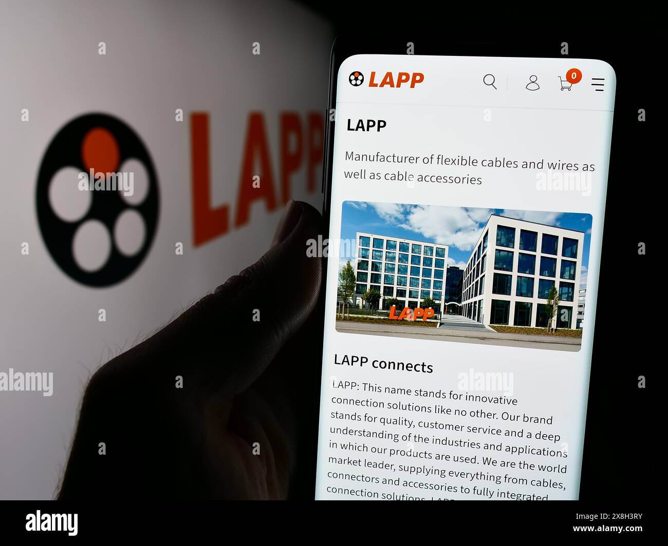 Persona che detiene un cellulare con pagina web della società tedesca via cavo Lapp Holding se davanti al logo aziendale. Messa a fuoco al centro del display del telefono. Foto Stock