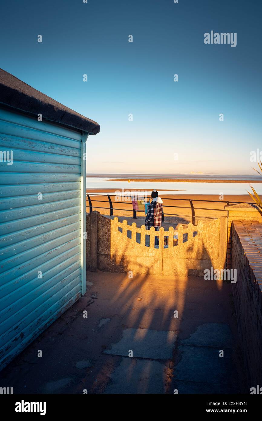 Capanne in legno con punto panoramico costiero, avvolte da un caldo bagliore di sole tramontante Foto Stock