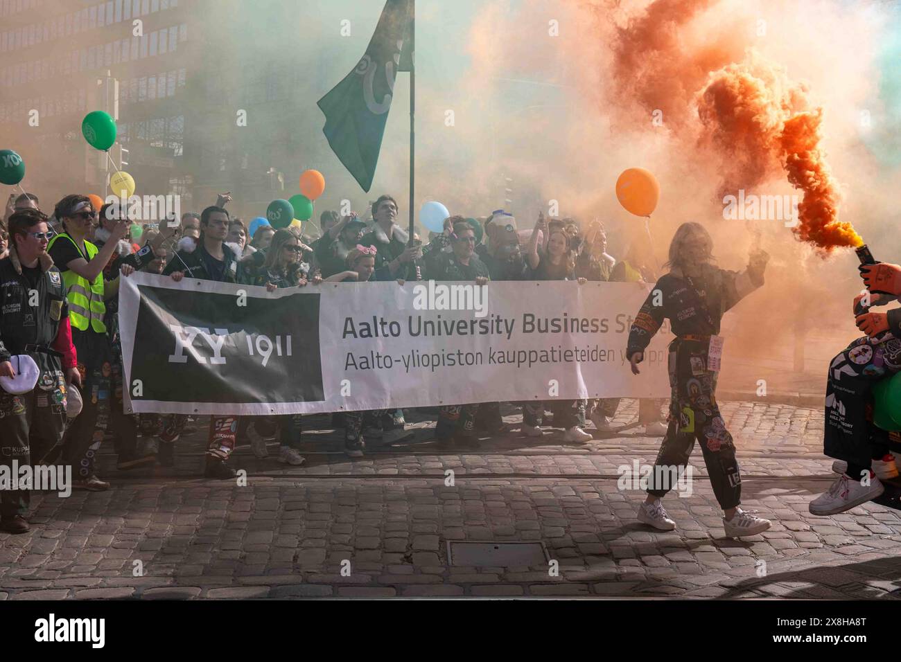 Gli studenti di affari dell'Università di Aalto e la granata di fumo d'arancia alla sfilata della vigilia di maggio a Helsinki, Finlandia Foto Stock