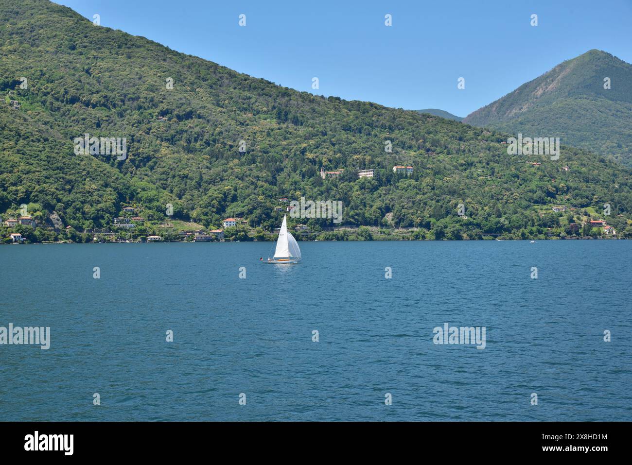 Yacht solitario che naviga sulle acque blu del Lago maggiore, Italia. Foto Stock