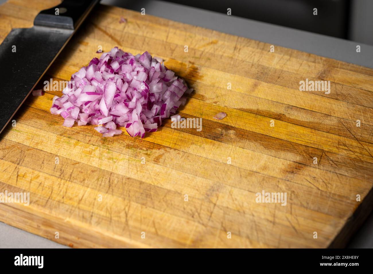 Cipolle rosse tritate su un tagliere di legno Foto Stock