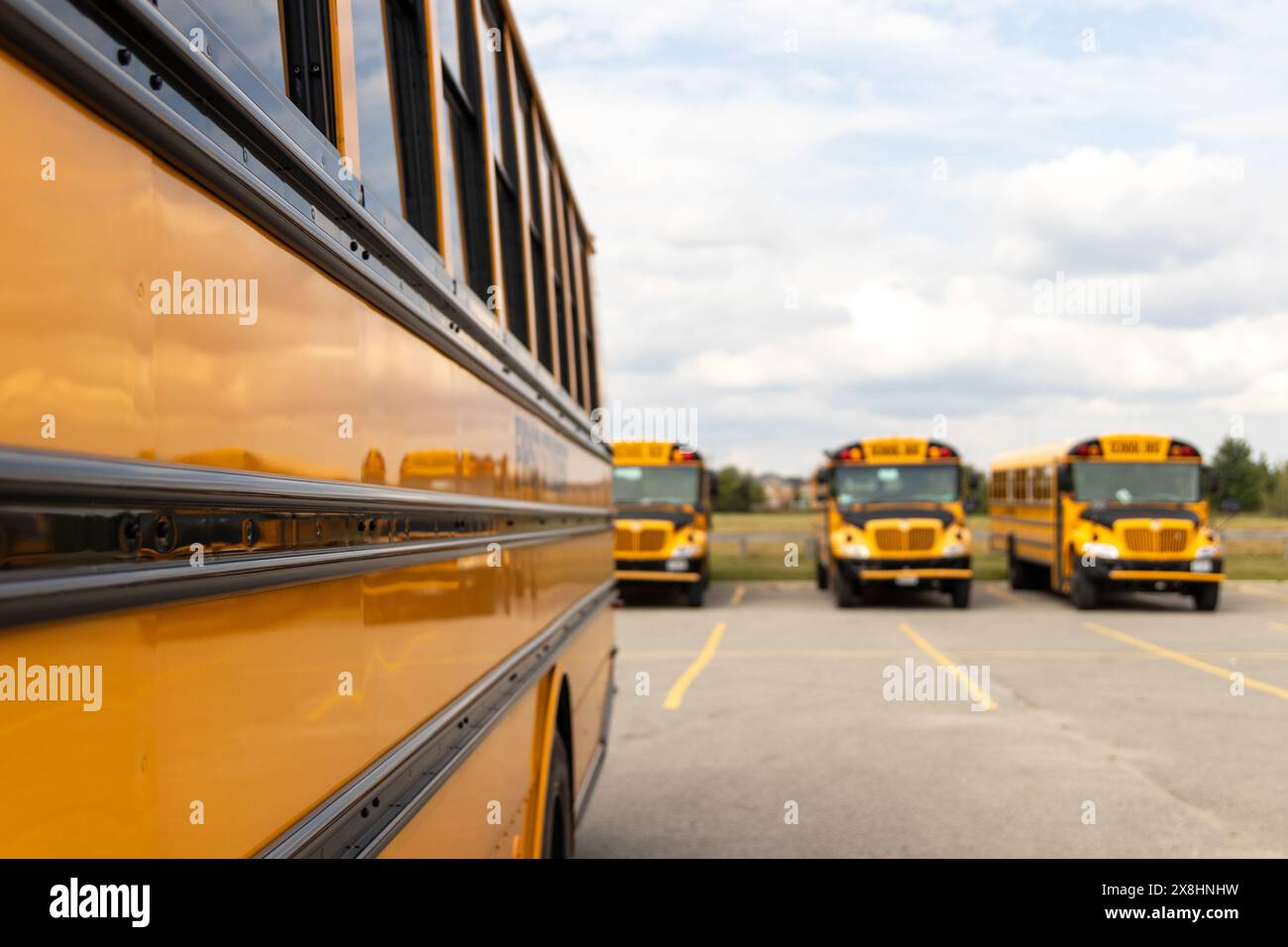 Vista laterale primo piano dello scuolabus giallo - parcheggiato - giornata di sole con nuvole nel cielo. Presa a Toronto, Canada. Foto Stock