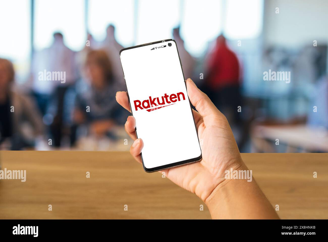 Tenere a mano il cellulare con il logo Rakuten e le persone sfocate sullo sfondo, Rio de Janeiro, Brasile, maggio 2024 Foto Stock