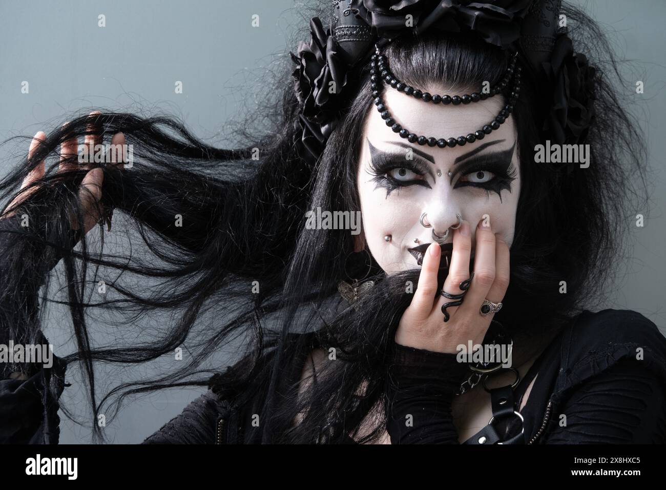 Ritratto sexy di una bellissima ragazza gotica con piercing e abiti neri con trucco bianco sul viso, lenti a contatto bianche, spazio copia Foto Stock