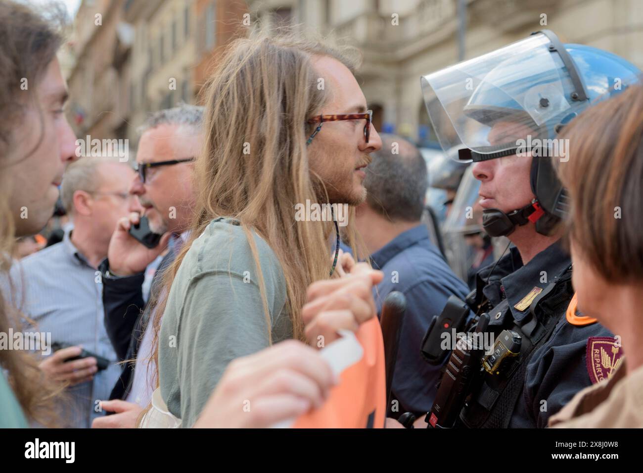 25 maggio 2024, Roma, Italia: Un attivista ambientalista sfida un poliziotto in equipaggiamento antisommossa durante il sit-in non autorizzato organizzato dagli attivisti ultima generazione a Roma. Circa un centinaio di persone hanno partecipato al sit-in di protesta non autorizzato organizzato attraverso i social media e i manifesti pubblicati in giro per la città da attivisti ambientali ultima Generatione (ultima generazione) con lo slogan ''We are Democracy'' a Roma. Con la loro disobbedienza civile non violenta cercano di attirare l'opinione pubblica sugli effetti del cambiamento climatico e chiedono al governo italiano di istituire una "Repara" Foto Stock