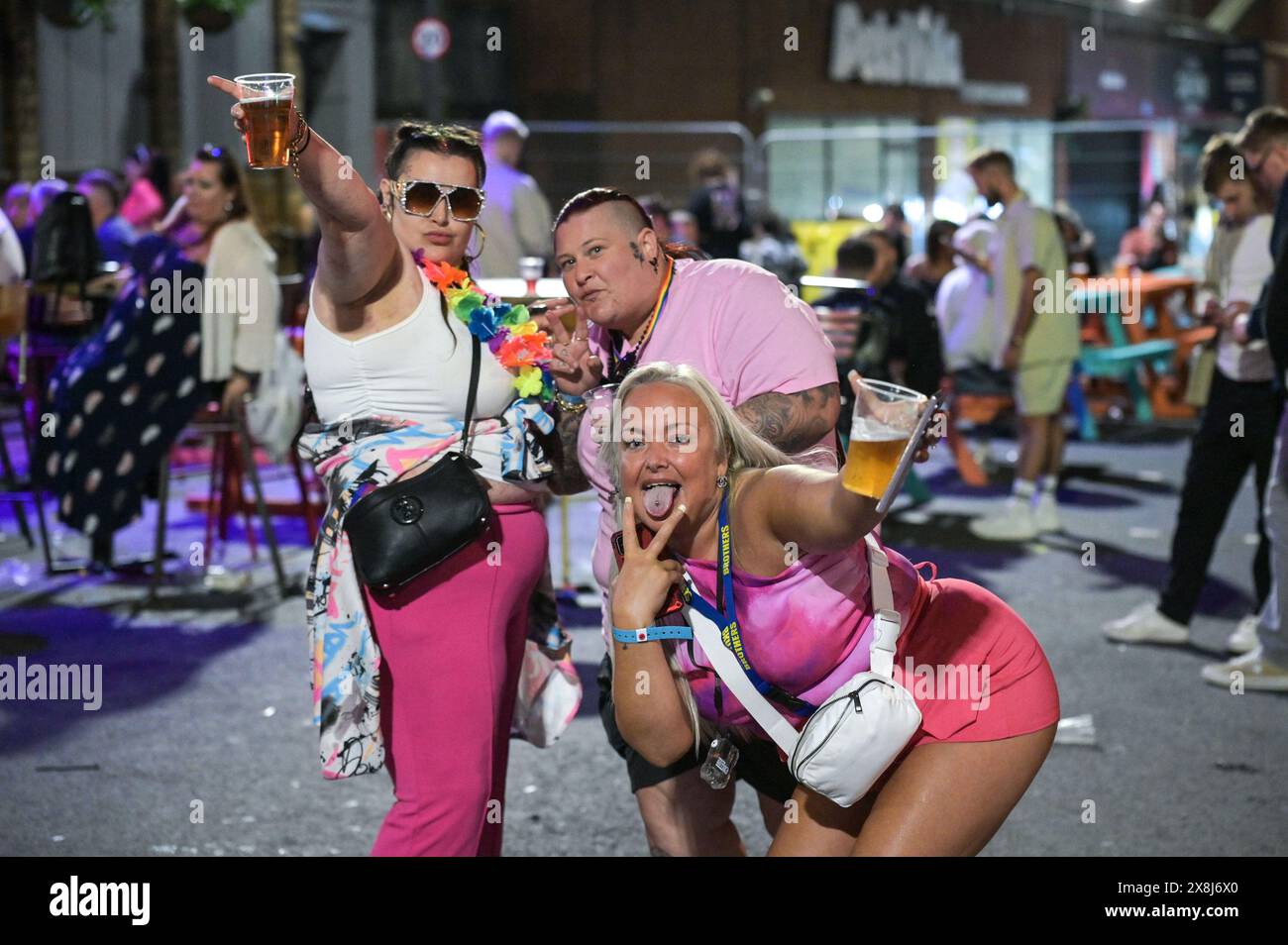 Broad Street, Birmingham, 26 maggio 2024 - la pioggia non è riuscita a smorzare gli spiriti mentre migliaia di festeggiamenti sono andati a Broad Street e al Gay Quarter di Birmingham il sabato sera mentre continuavano le festività. I festaioli si sono recati sulla Strip, facendo uscire i locali notturni di Rosies e Heidi. Diversi rivelatori sono stati anche avvistati mentre tornavano a casa dall'evento Pride della città, con un gruppo di ragazze in posa rosa con alcuni agenti di polizia. Credito: Interrompi stampa Media/Alamy Live News Foto Stock