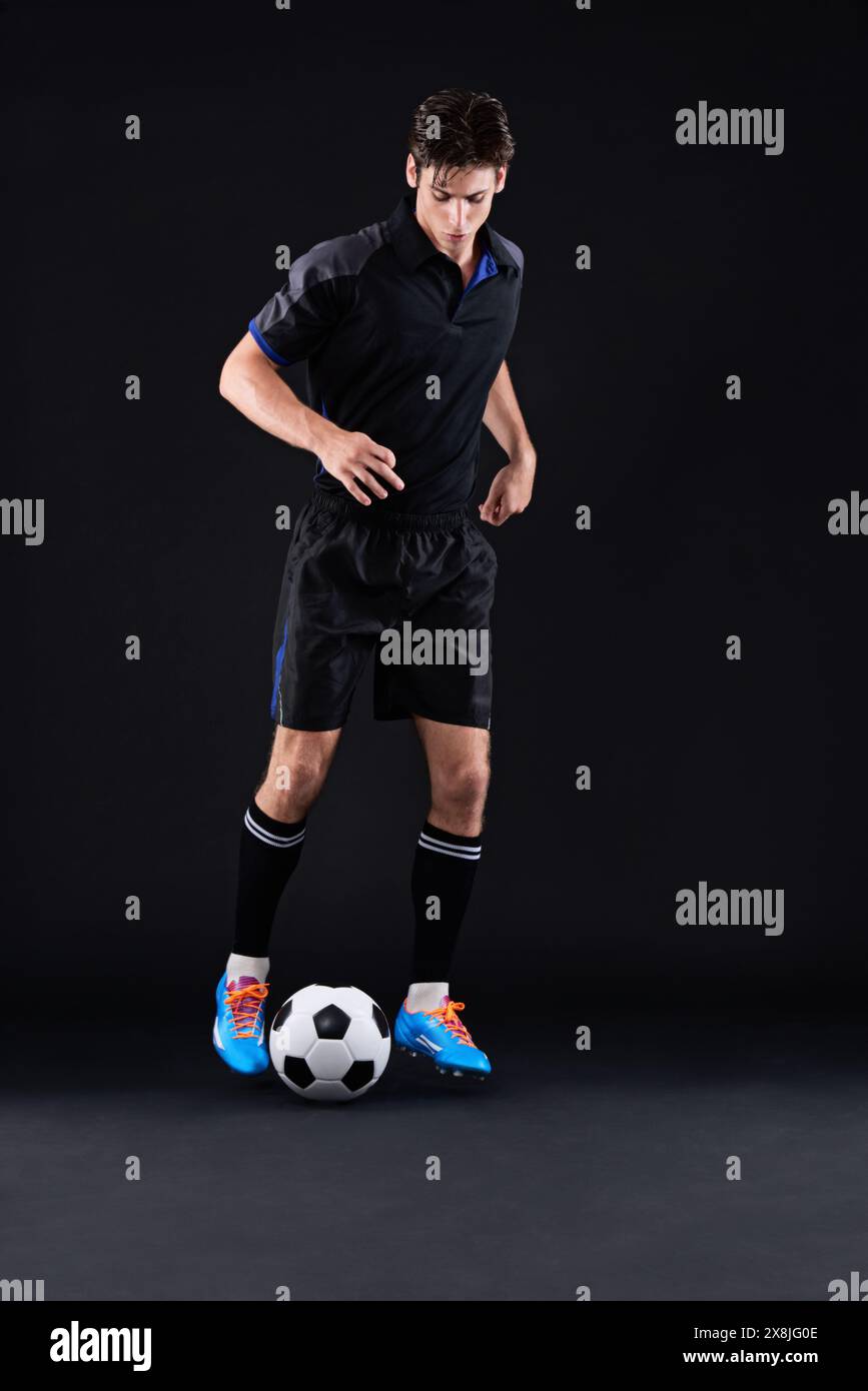 Fitness, studio e uomo con calcio per allenamenti sportivi con esercizi isolati su sfondo nero. Dribbling, talento e tecnica per il freestyle Foto Stock