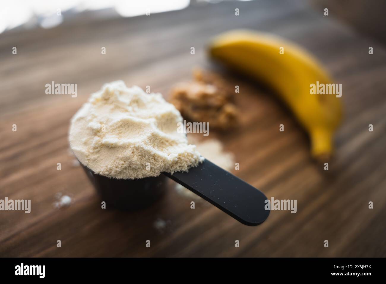 Alcuni alimenti sani come proteine in polvere, banane e noci su un tavolo di legno Foto Stock