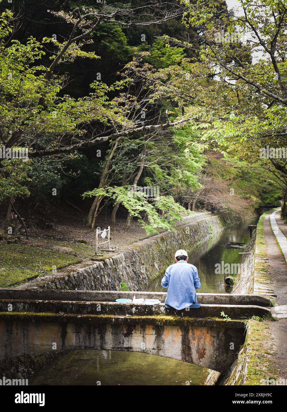 Uomo giapponese seduto in un ponte mentre pesca a Kyoto (Tetsugaku No Michi) Foto Stock