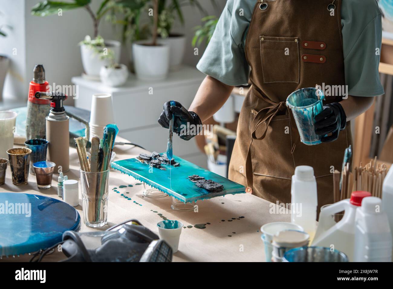 Processo di realizzazione di un primo piano artigianale utilizzando materiali moderni per la progettazione, resina epossidica liquida, legno, pietra. Foto Stock