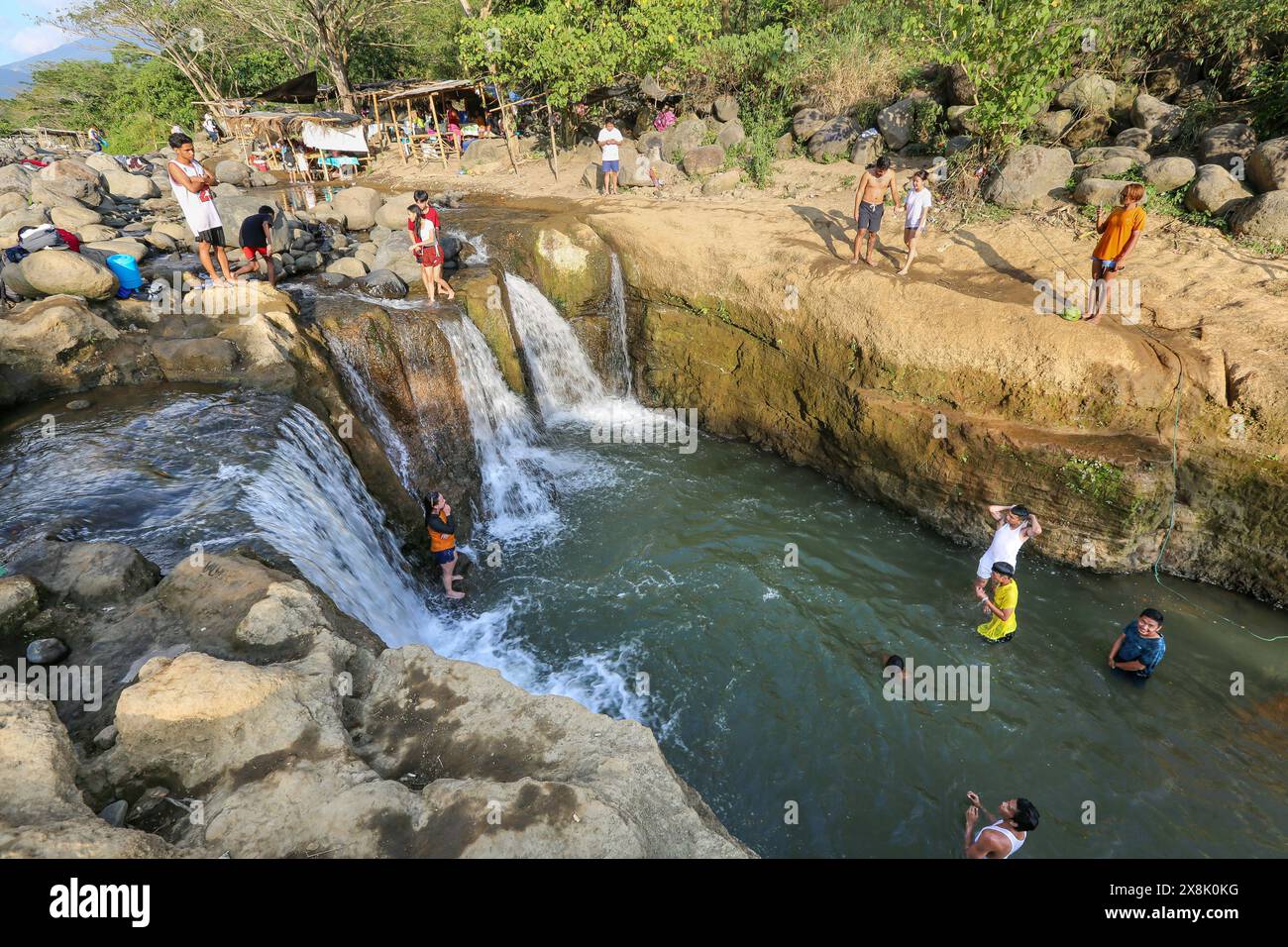 Dolores, Filippine. 25 maggio 2024: I filippini affollano torrenti che non si sono prosciugati per sfuggire al caldo soffocante delle città. A Calabarzon, alcuni trovano rifugio a Paeng Falls, una nuova destinazione creata dal tifone Paeng (2022). In streaming dal Monte Banahaw, una montagna sacra soggetta a frane, erosione e alluvioni distruttive, il letto del fiume Lagnas si è placato per formare queste cascate molto apprezzate in quanto l'arcipelago e il sud-est asiatico soffrono di forti ondate di caldo e siccità a causa di El Nino che terminerà con la depressione tropicale Aghon, la prima tempesta a colpire il paese quest'anno. Crediti: Kevin Izorce/Alamy Live News Foto Stock