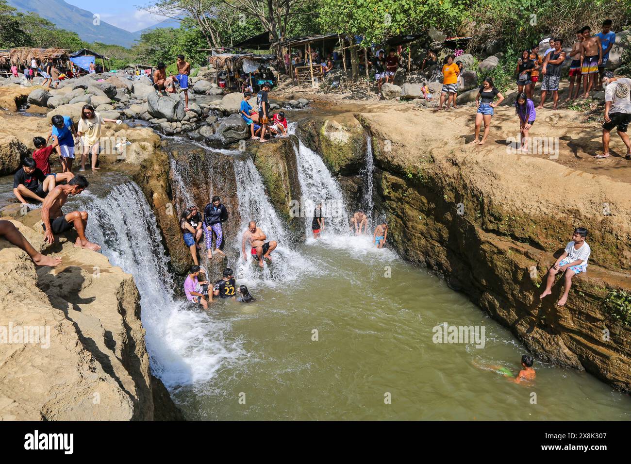 Dolores, Filippine. 25 maggio 2024: I filippini affollano torrenti che non si sono prosciugati per sfuggire al caldo soffocante delle città. A Calabarzon, alcuni trovano rifugio a Paeng Falls, una nuova destinazione creata dal tifone Paeng (2022). In streaming dal Monte Banahaw, una montagna sacra soggetta a frane, erosione e alluvioni distruttive, il letto del fiume Lagnas si è placato per formare queste cascate molto apprezzate in quanto l'arcipelago e il sud-est asiatico soffrono di forti ondate di caldo e siccità a causa di El Nino che terminerà con la depressione tropicale Aghon, la prima tempesta a colpire il paese quest'anno. Crediti: Kevin Izorce/Alamy Live News Foto Stock