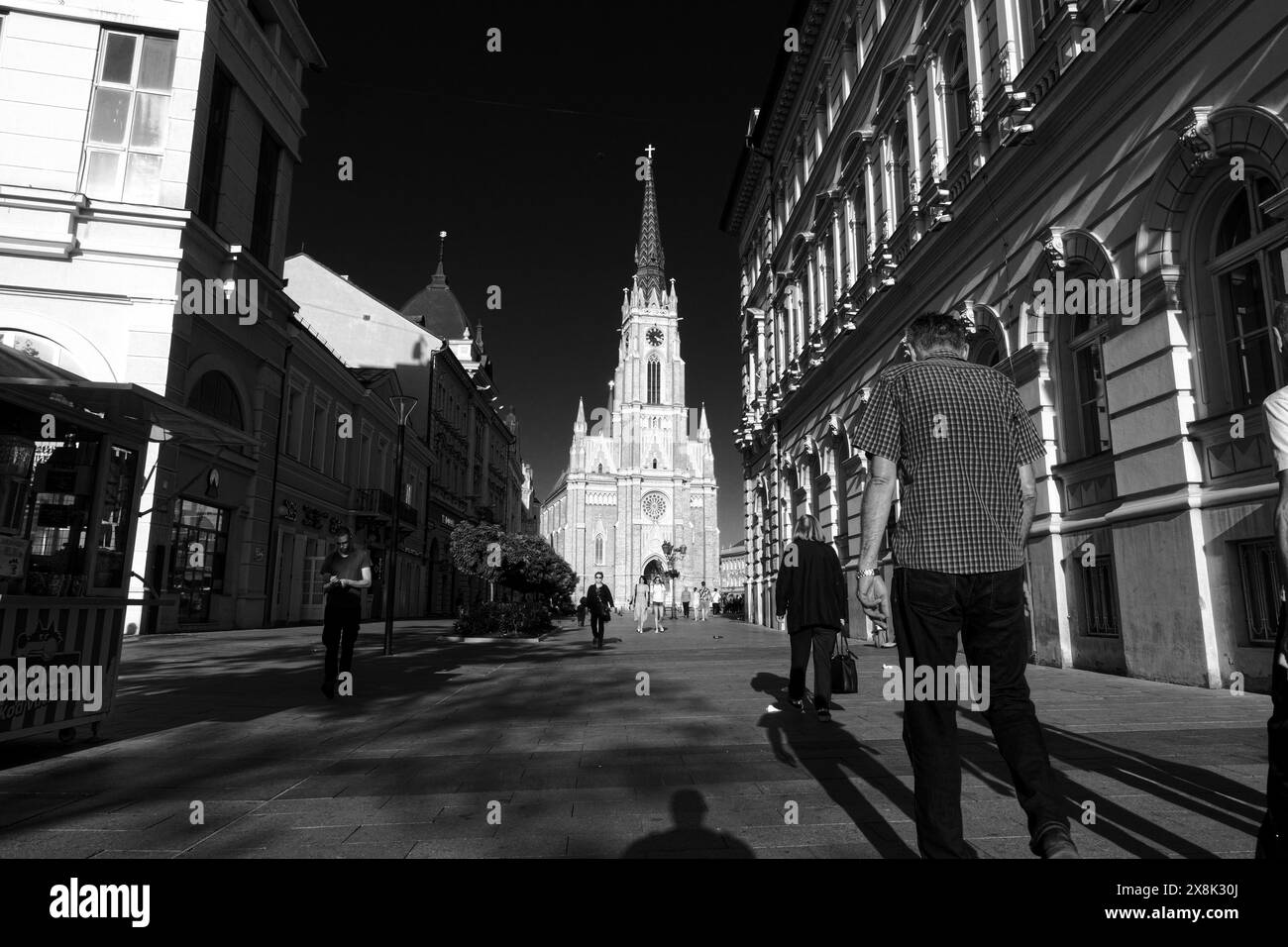 Persone bianche e nere che camminano sullo sfondo nome della Chiesa di Maria a Novi Sad, Vojvodina, Serbia Foto Stock