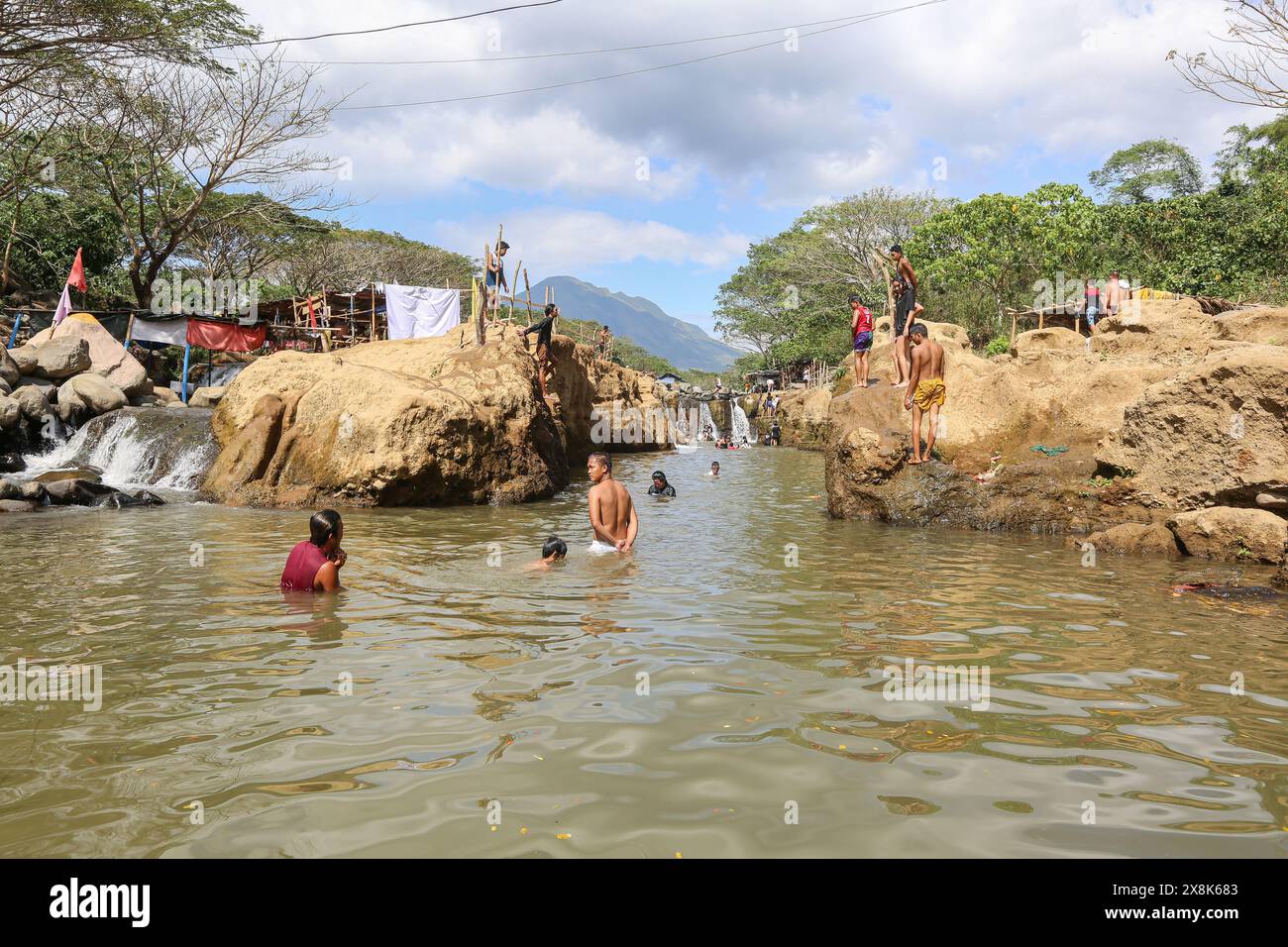 Dolores, Filippine. 25 maggio 2024: I filippini affollano torrenti che non si sono prosciugati per sfuggire al caldo soffocante delle città. A Calabarzon, alcuni trovano rifugio a Paeng Falls, una nuova destinazione creata dal tifone Paeng (2022). In streaming dal Monte Banahaw, una montagna sacra soggetta a frane, erosione e alluvioni distruttive, il letto del fiume Lagnas si è placato per formare queste cascate molto apprezzate in quanto l'arcipelago e il sud-est asiatico soffrono di forti ondate di caldo e siccità a causa di El Nino che terminerà con la depressione tropicale Aghon, la prima tempesta a colpire il paese quest'anno. Crediti: Kevin Izorce/Alamy Live News Foto Stock