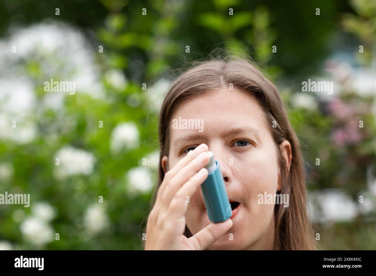 La giovane donna soffre di febbre da fieno e inala spray per l'asma all'aperto, Friburgo, Baden-Wuerttemberg, Germania Foto Stock