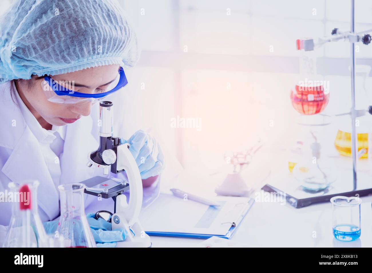 Scienziata femminile guardare al microscopio, scienza provetta di prova analizzare campione scientifico in laboratorio esperimento di ricerca biotech fare coltivare vaccino agai Foto Stock