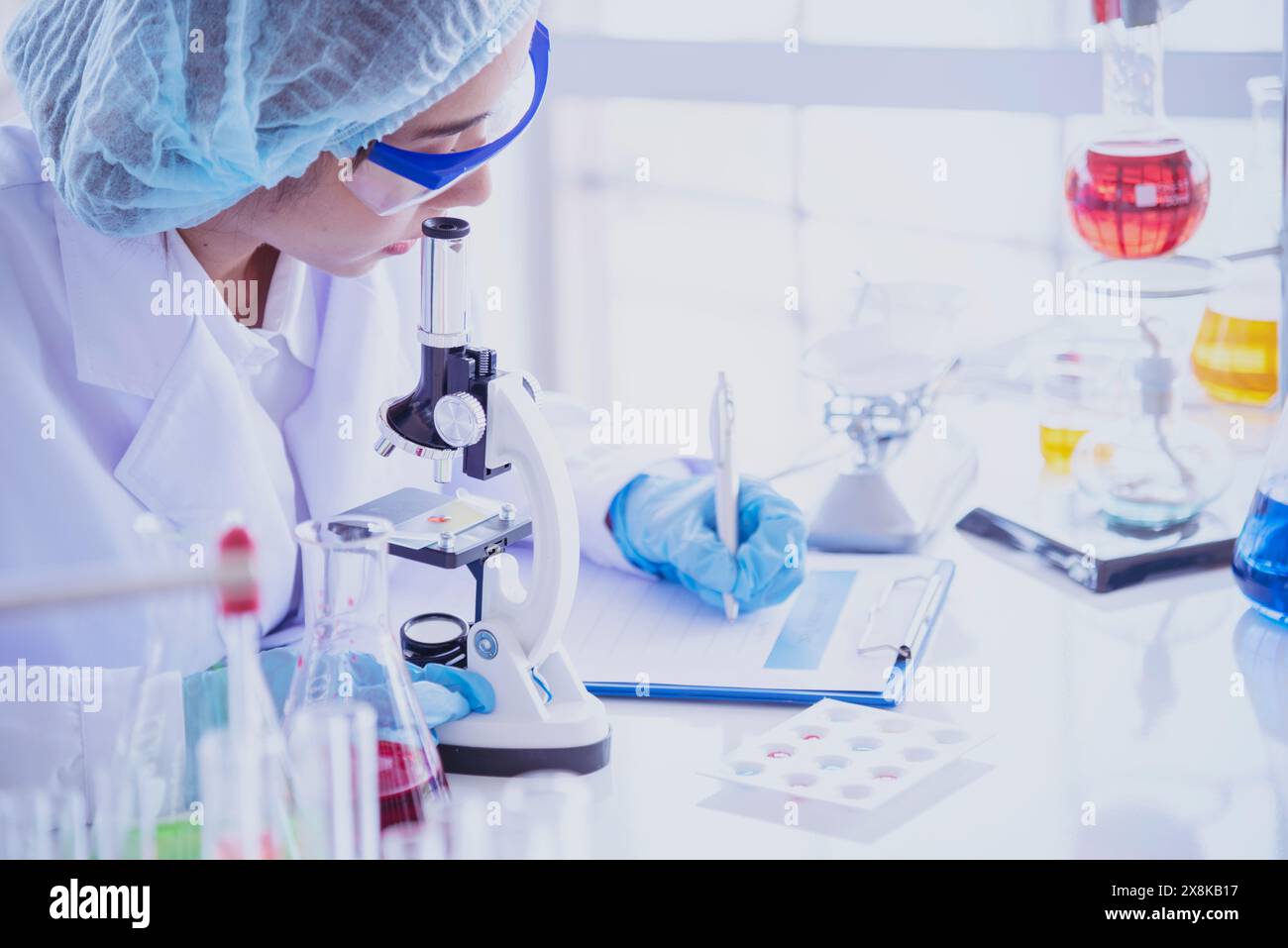 Scienziata femminile guardare al microscopio, scienza provetta di prova analizzare campione scientifico in laboratorio esperimento di ricerca biotech fare coltivare vaccino agai Foto Stock