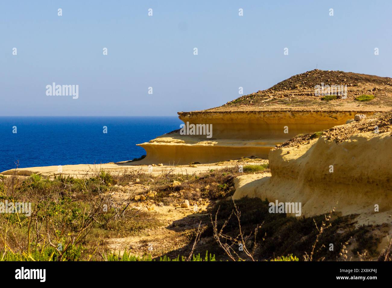 Scogliera che si affaccia sul mare e sul cielo blu, la bellezza serena della natura. Foto Stock