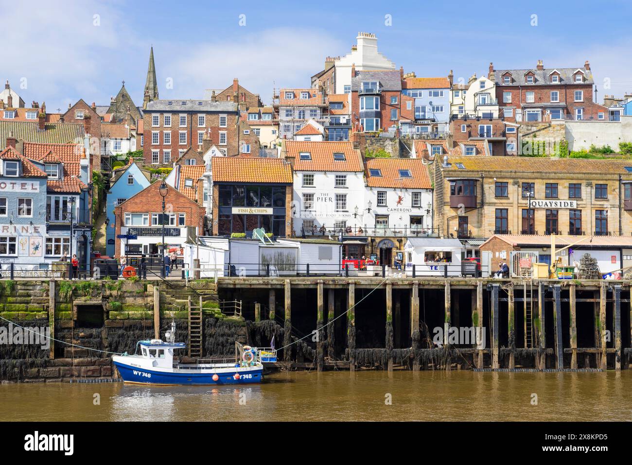 Whitby Yorkshire Whitby Harbour con una piccola barca da pesca nel porto e il mercato ittico sul molo Whitby North Yorkshire Inghilterra Regno Unito Europa Foto Stock