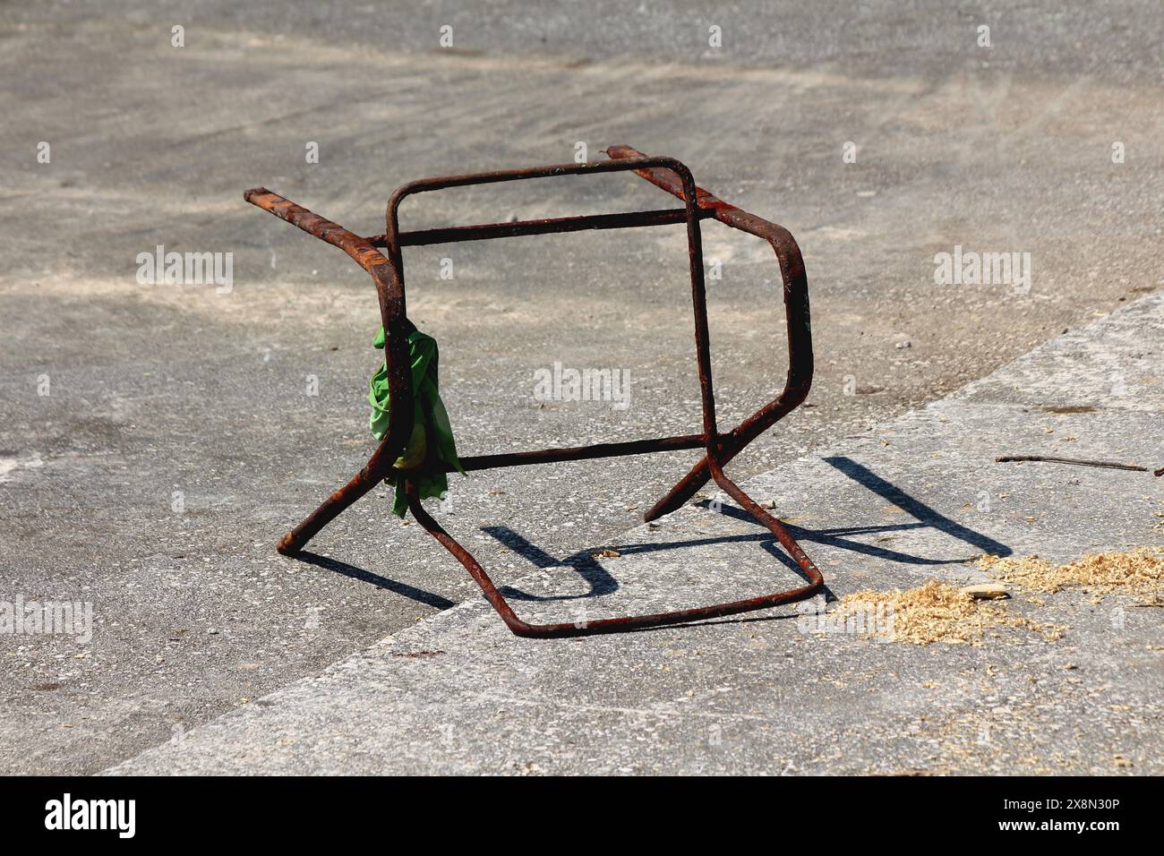 Telaio in metallo della sedia da spiaggia completamente arrugginito rotto con vecchia t-shirt verde fatiscente avvolta intorno al mare dopo aver pulito la spazzatura dell'oceano Foto Stock