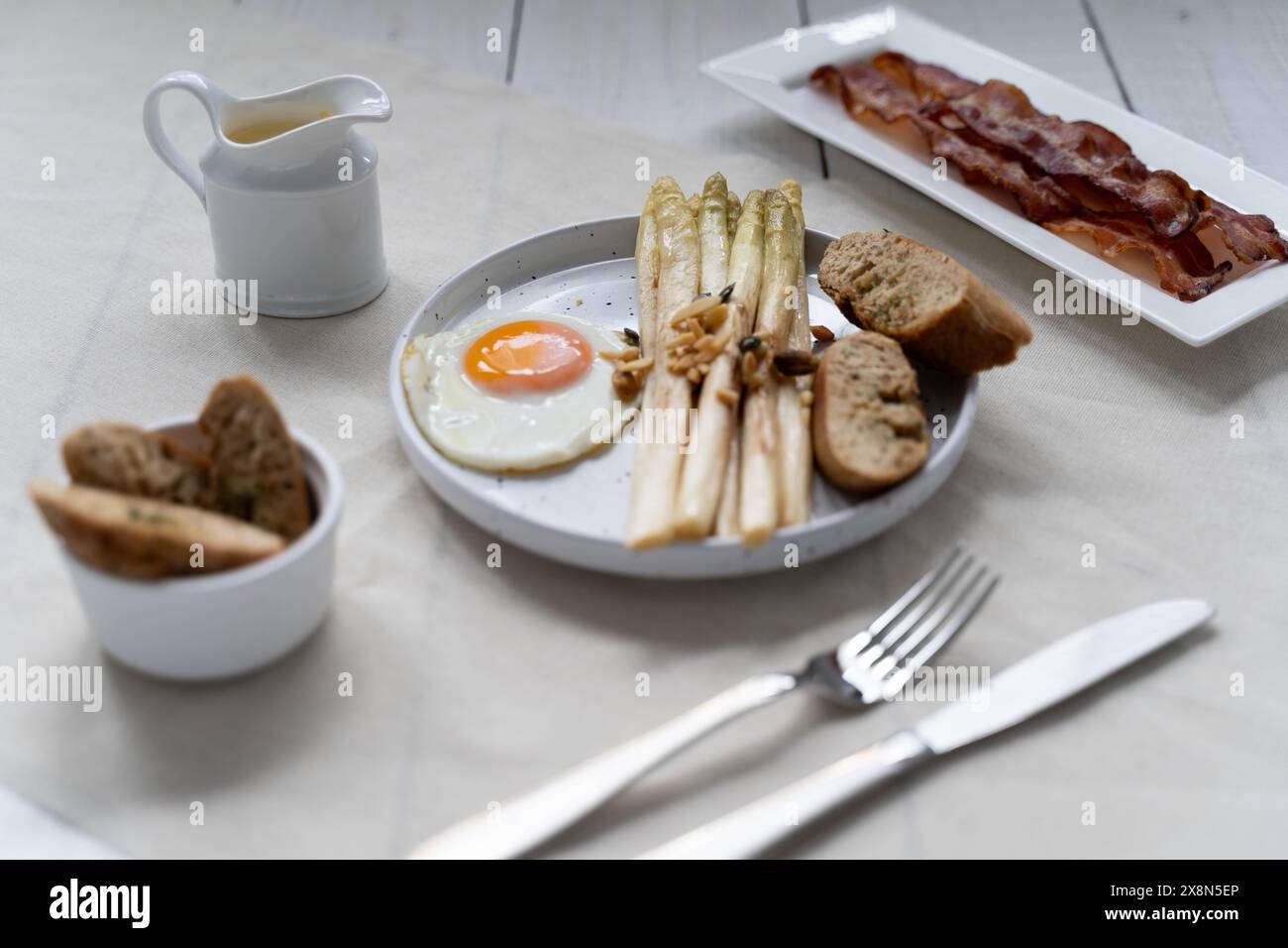 Asparagi bianchi serviti con uova fritte e pancetta. Gli asparagi, che rappresentano le fibre alimentari, sono molto popolari in Germania durante Spargelzeit Foto Stock